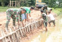Hindari longsoran pada pelebaran jalan sepanjang sepanjang 750 meter, Satgas TMMD dan warga kampung Jawi secara gotong royong lakukan pemasangan pancang kayu sebagai penopang kanan kiri jalan tersebut.