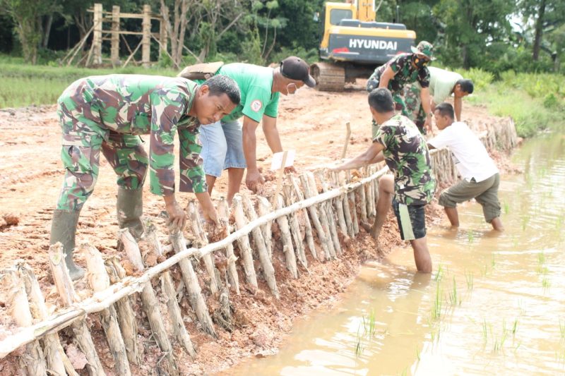 Hindari longsoran pada pelebaran jalan sepanjang sepanjang 750 meter, Satgas TMMD dan warga kampung Jawi secara gotong royong lakukan pemasangan pancang kayu sebagai penopang kanan kiri jalan tersebut.