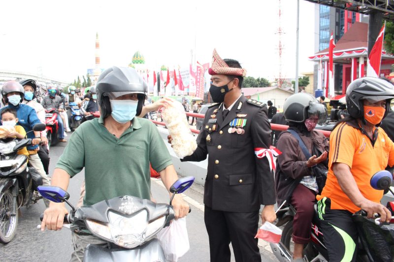 Jajaran Polda Sumsel mengenakan topi adat Palembang (Tanjak) saat detik detik Proklamasi membagikan Telok Abang bagi pengendara yang melintas di depan Mapolda Sumsel