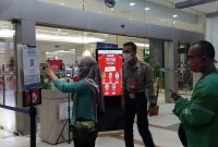 sebelum memasuki mal, Pengunjung melakuan scanning barcode di depan pintu masuk dengan pengawasan pihak sekuriti mal, Minggu [31/10] malam.