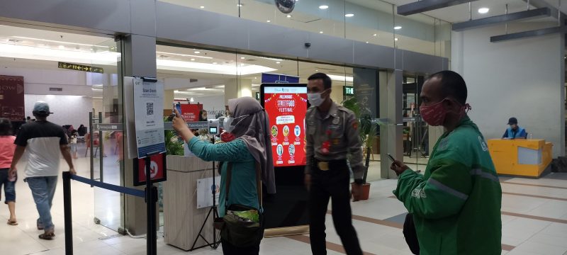 sebelum memasuki mal, Pengunjung melakuan scanning barcode di depan pintu masuk dengan pengawasan pihak sekuriti mal, Minggu [31/10] malam.