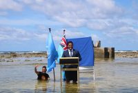 Dikutip dari akun Facebook@Ministry of Justice, Communication and Foreign Affairs, Tuvalu Government, Senin [8/11], Simon Kofe MP berdiri dengan setelan jas dan dasi di podium yang digelar di laut, dengan menggunakan jas, dan celana digulung sebatas lutut.