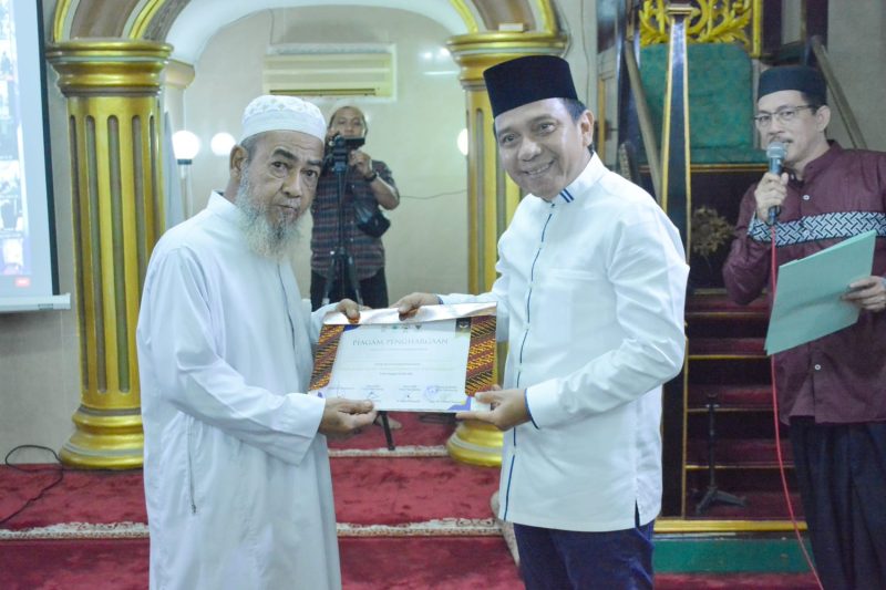 Kepala Dinas Kominfo Palembang, H Edison menyerahkan piagam rekor MURI kepada Ketua Masjid Jamik Sungai Lumpur 