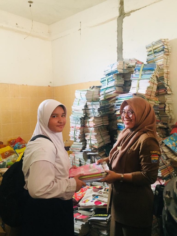 Kepala SMPN 19 Palembang Sri Wahyuni memberikan buku pelajaran baru bagi siswa yang terdampak banjir. 