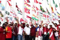 Para pecinta sepak bola Qatar berfoto bersama dengan latar belakang bendera negara peserta jelang berlangsungnya Piala Dunia FIFA Qatar 2022, di Doha, Qatar, Jumat (18/11/2022). (Foto: Reuters/Marko Djurica)