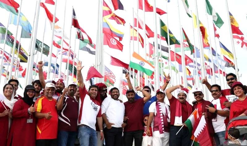 Para pecinta sepak bola Qatar berfoto bersama dengan latar belakang bendera negara peserta jelang berlangsungnya Piala Dunia FIFA Qatar 2022, di Doha, Qatar, Jumat (18/11/2022). (Foto: Reuters/Marko Djurica)