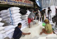 Pekerja mengemas beras ke dalam karung di Pasar Induk Beras Cipinang, Jakarta, Selasa (26/1/2021)