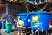 Seorang sedang mengisi air bersih untuk masyarakat Cianjur ke dalam tangki penampungan air. Dokumentasi/ PUPR