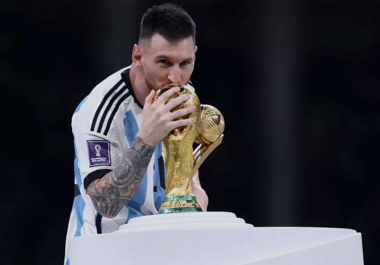Kapten Timnas Argentina Lionel Messi mencium Trofi juara Piala Dunia Qatar 2022 usai menerima gelar pemain terbaik. Argentina berhasil meraih gelar juara usai mengalahkan Prancis lewat drama adu penalti Pada laga di Stadion Lusail Iconic, Qatar, Minggu (18/12/2022). (Foto:Istimewa/FIFA)