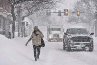 Saat salju menumpuk, seorang pejalan kaki, Gina Hanson, dari Brattleboro, Vt., Berjalan di Jalan Utama Brattleboro selama badai salju pada Kamis, 17 Desember 2020. (AP/Kristopher Radder)