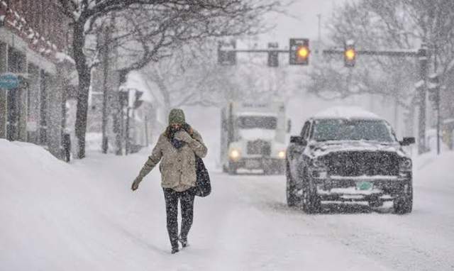 Saat salju menumpuk, seorang pejalan kaki, Gina Hanson, dari Brattleboro, Vt., Berjalan di Jalan Utama Brattleboro selama badai salju pada Kamis, 17 Desember 2020. (AP/Kristopher Radder)