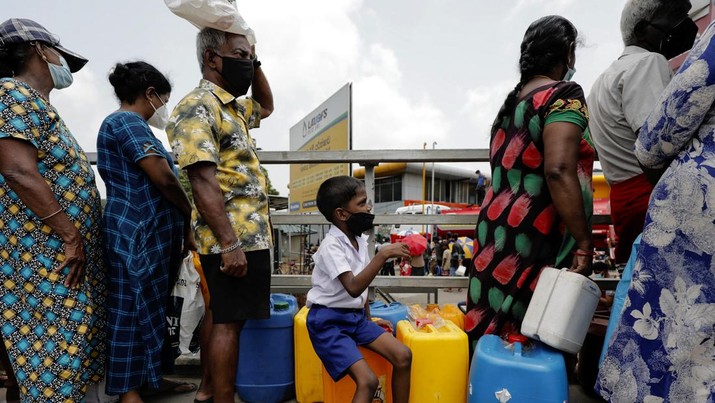 Seorang anak laki-laki duduk di wadah kosong bersama orang tuanya saat mereka menunggu untuk membeli minyak tanah di tengah kekurangan gas rumah tangga akibat krisis ekonomi negara, di sebuah SPBU di Kolombo (Foto: REUTERS)
