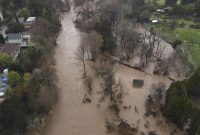Banjir Sungai San Lorenzo yang dilanda badai membanjiri sepanjang Ocean Street Extension di Santa Cruz, California, di sebelah kanan, Senin (9/1/2023) (Foto: AP)
