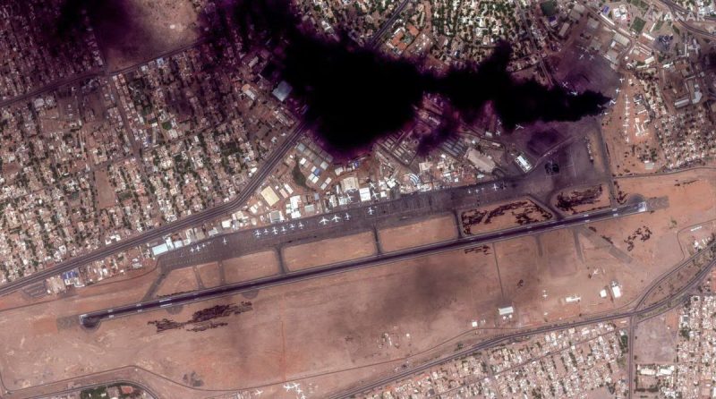 Citra satelit menunjukkan asap mengepul di Bandara Internasional Khartoum, Minggu (16/4/2023)