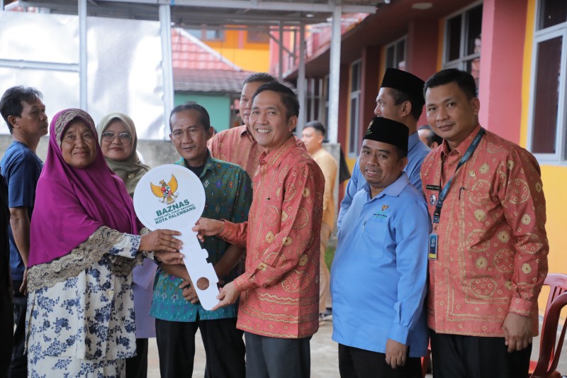 Sekretaris Daerah [Sekda] Kota Palembang Ratu Dewa menyerahkan kunci rumah [usai dibedah dengan dana Zakat ASN] ke pada Rukesih