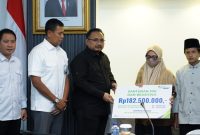 Menag Yaqut Cholil Qoumas menyerahkan secara simbolis klaim Petugas Pembimbing Ibadah Haji tahun 2023 dari BPJS Ketenagakerjaan kepada Khanatus Sa'diah, Selasa (15/8/2023)