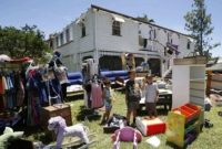 Anak-anak menunggu dikelilingi perabot dan harta benda lainnya, setelah warga mengosongkan rumah mereka yang sebagian rusak akibat Siklon Marcia di Yeppoon (Foto: Reuters)